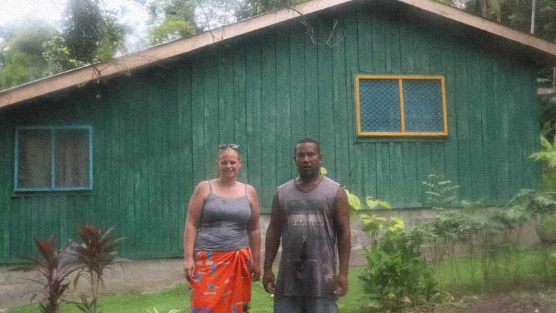 PALM worker Pattson standing with a woman in front of a newly built green house, representing his achievements through the program.