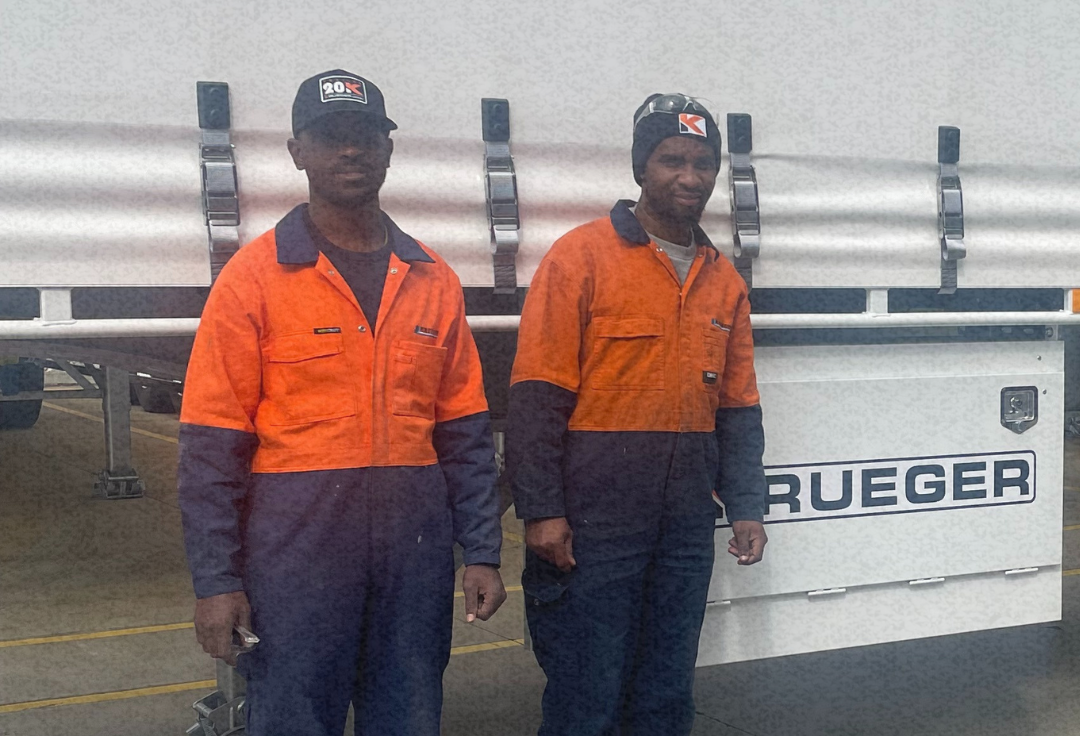 Four people stand in front of a client truck, including two workers in high-vis uniforms, a client and a recruitment manager, representing skilled trades recruitment.