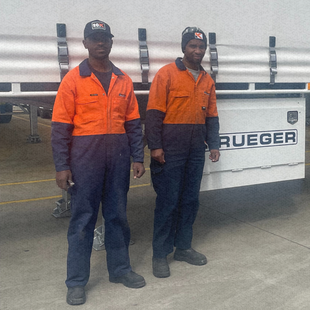 Four people stand in front of a client truck, including two workers in high-vis uniforms, a client and a recruitment manager, representing skilled trades recruitment.