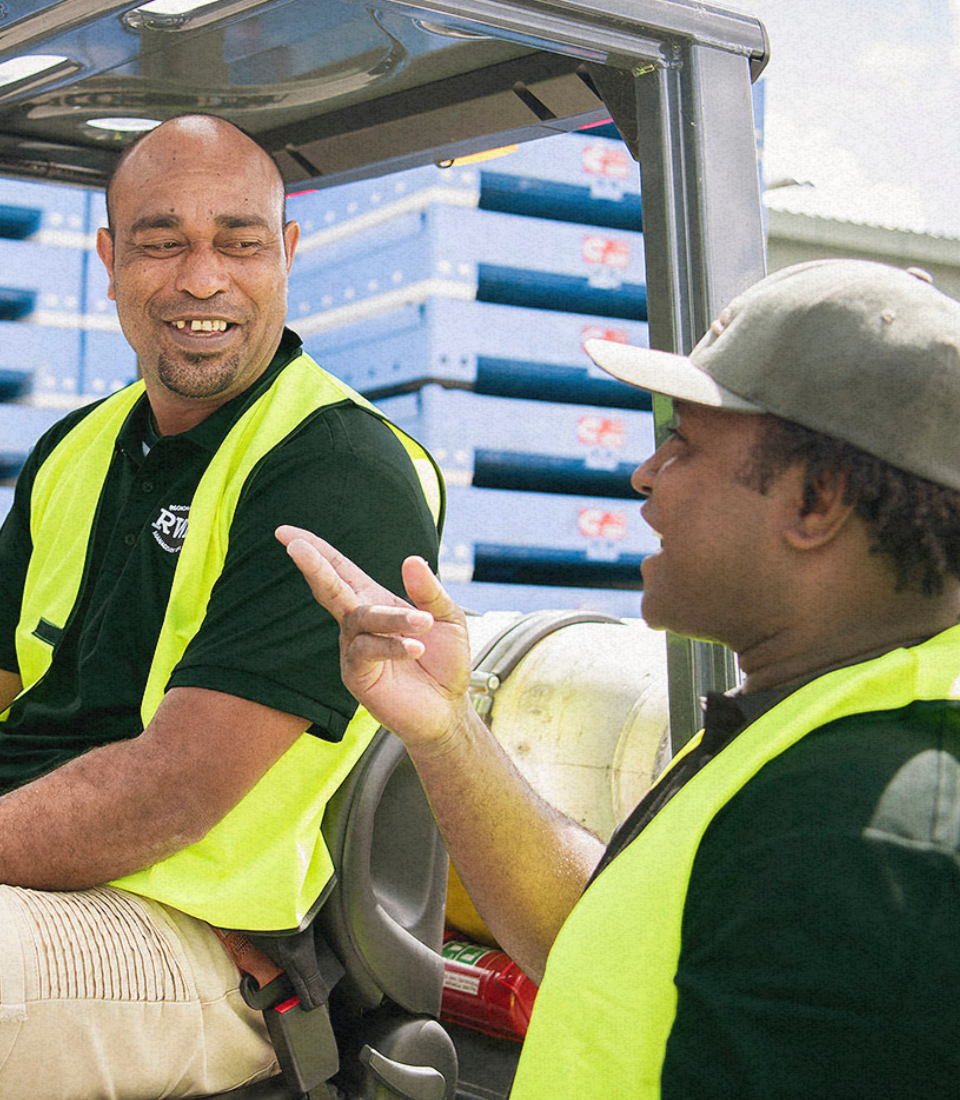 A man in an orange vest is driving an orange forklift
