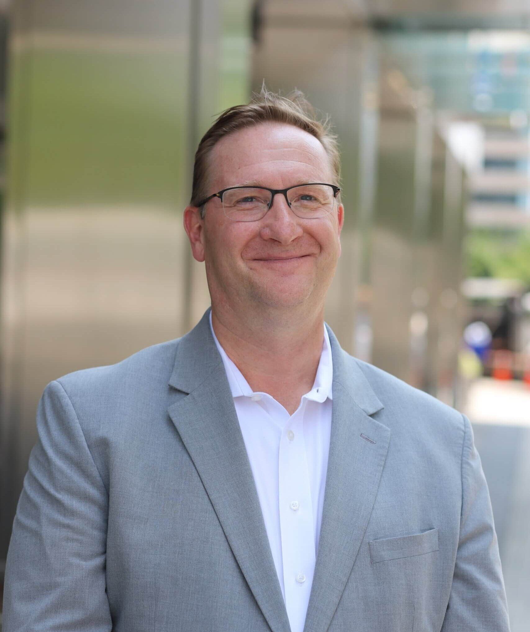 A man in a suit and tie is smiling for the camera.