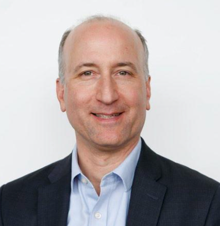 A man in a suit and blue shirt is smiling for the camera.