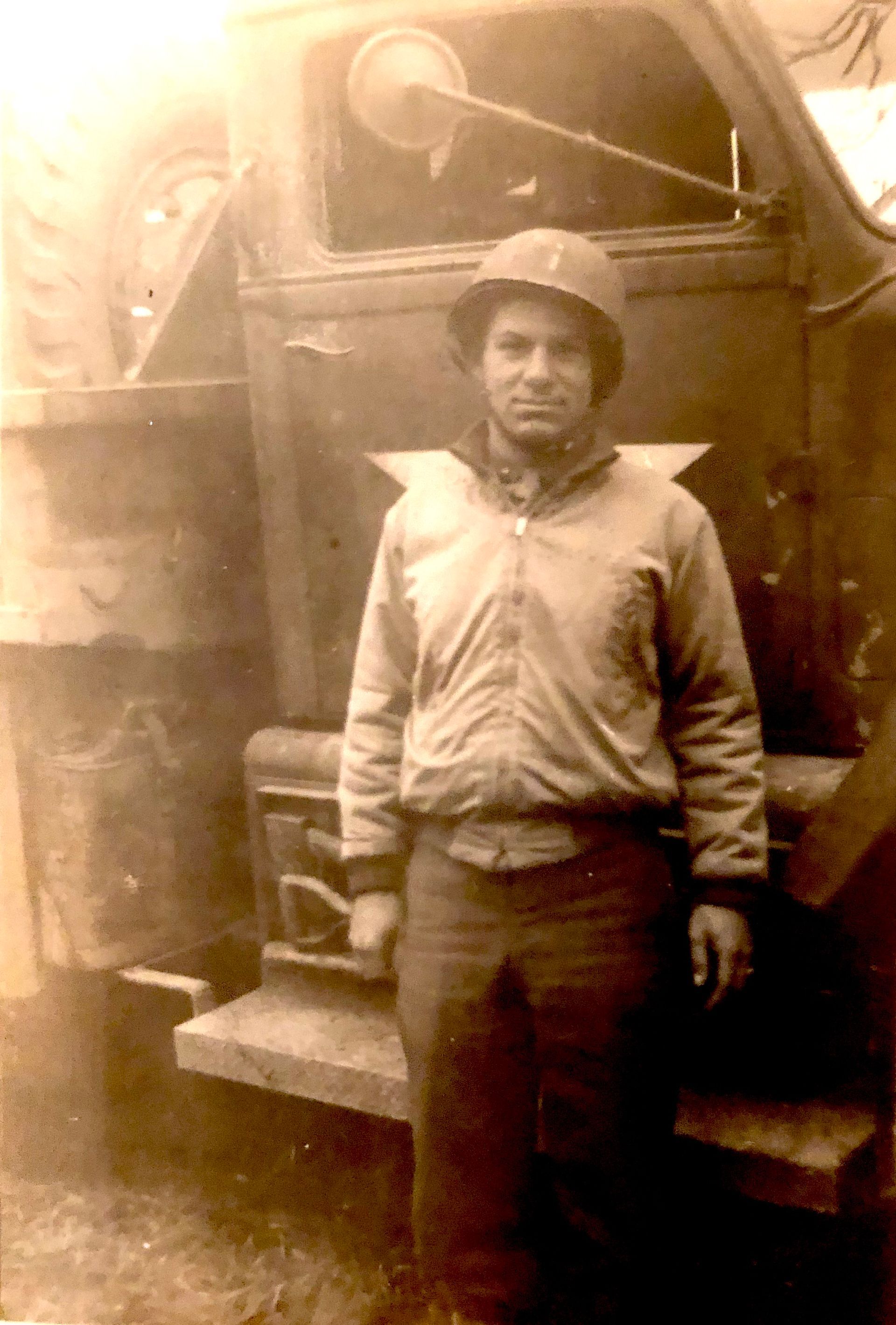 A man in a helmet is standing in front of a truck.