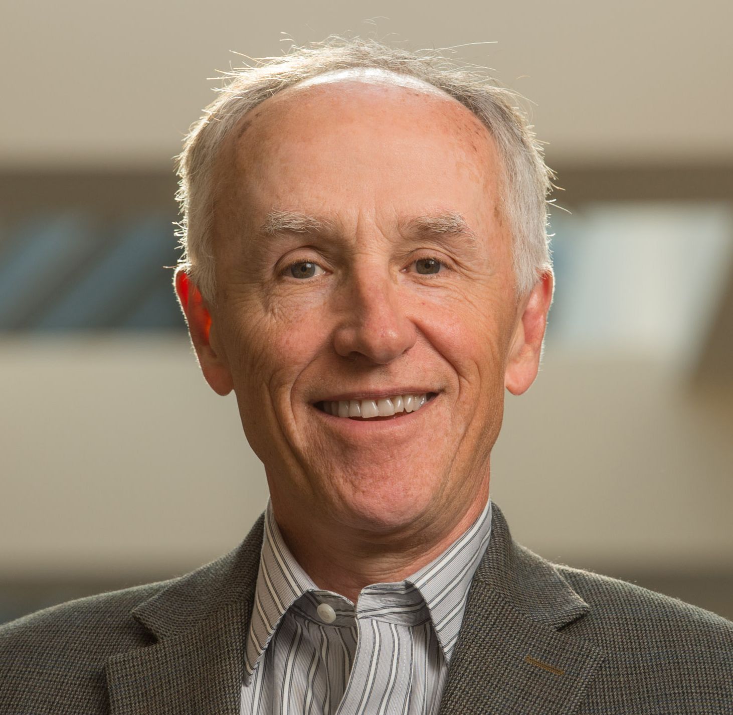 A man in a suit and striped shirt is smiling for the camera.