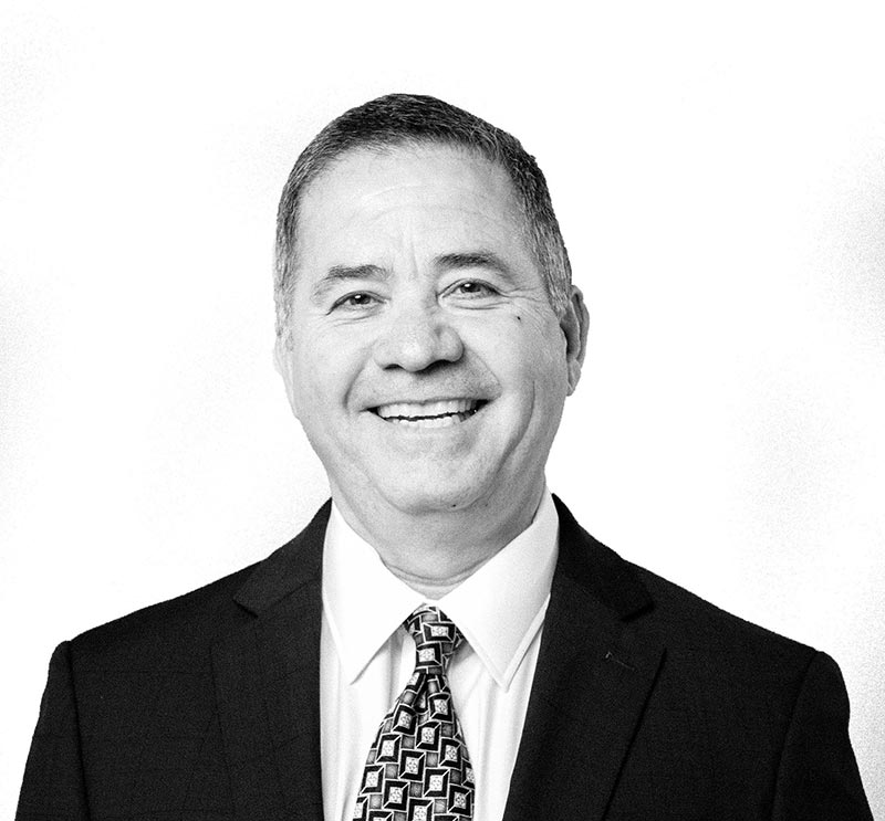 A man in a suit and tie is smiling in a black and white photo.