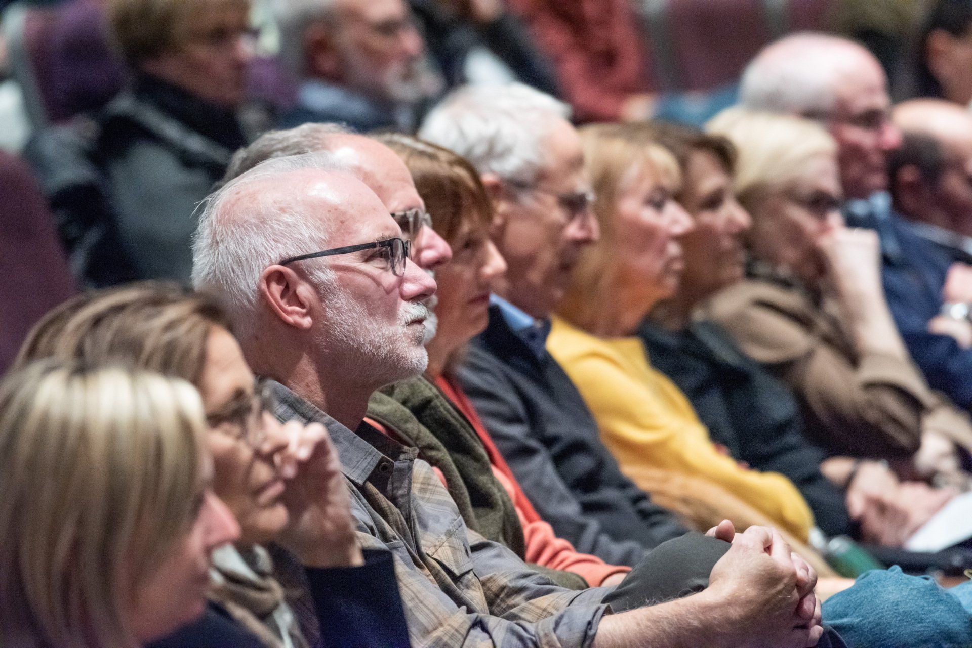 A group of people are sitting in a theater watching a presentation.