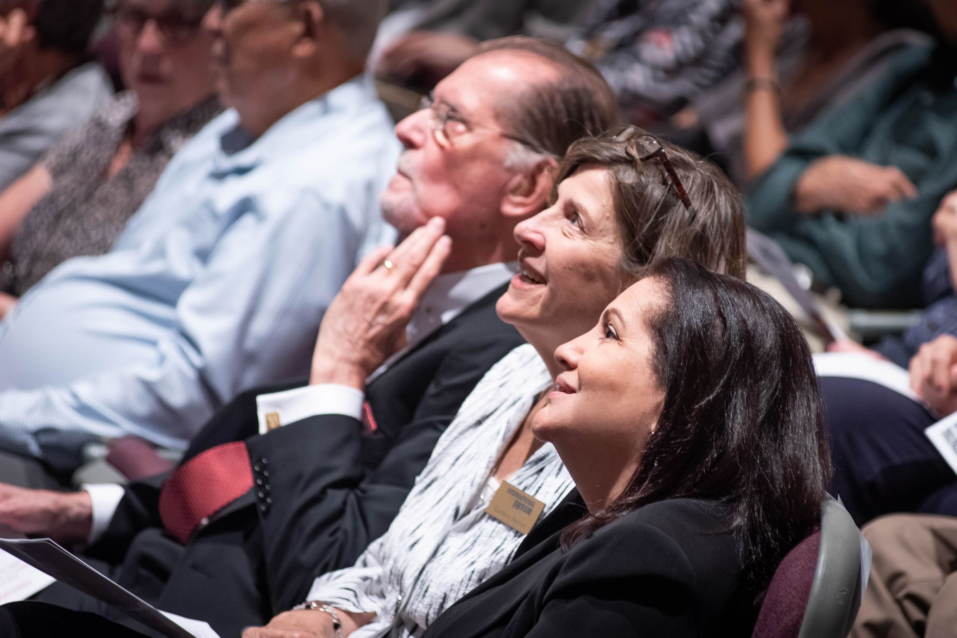 A group of people are sitting in a theater laughing.