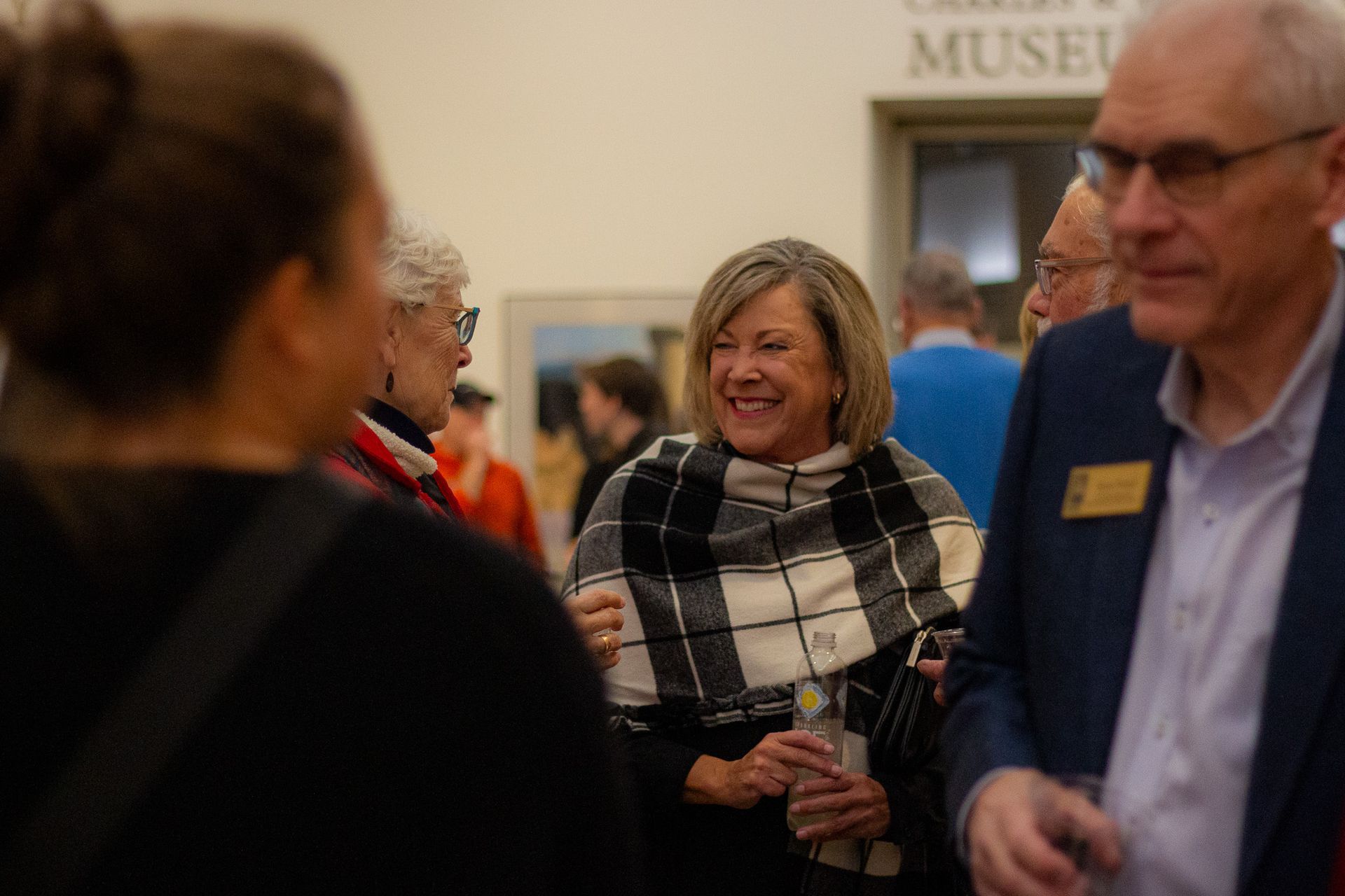 A group of people are standing in a museum talking to each other.