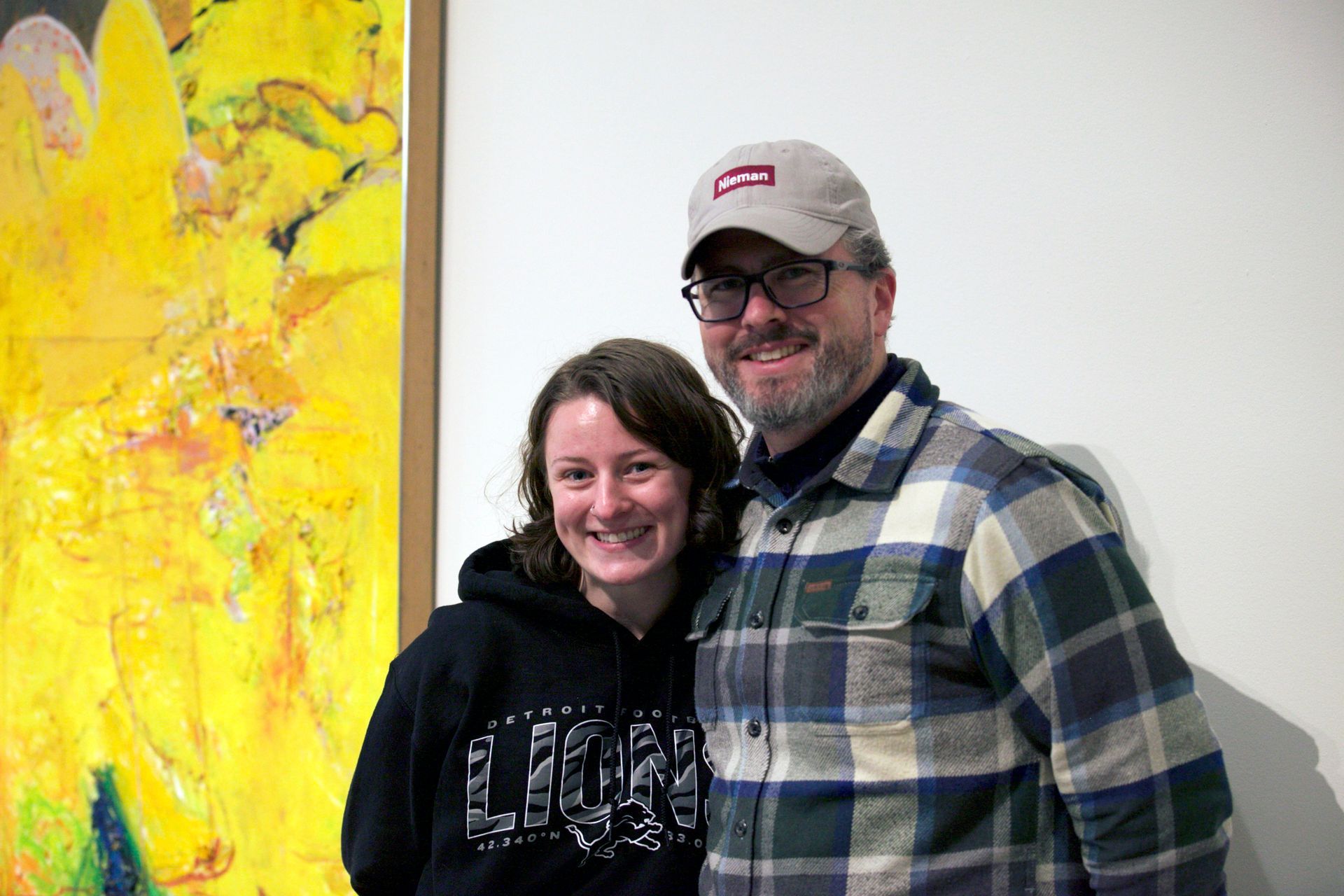 A man and a woman are posing for a picture in front of a painting.