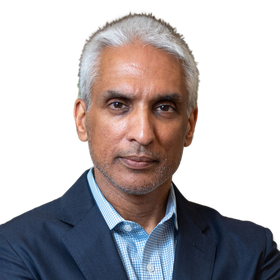 Portrait of a man in a navy suit and blue checkered shirt against a white background