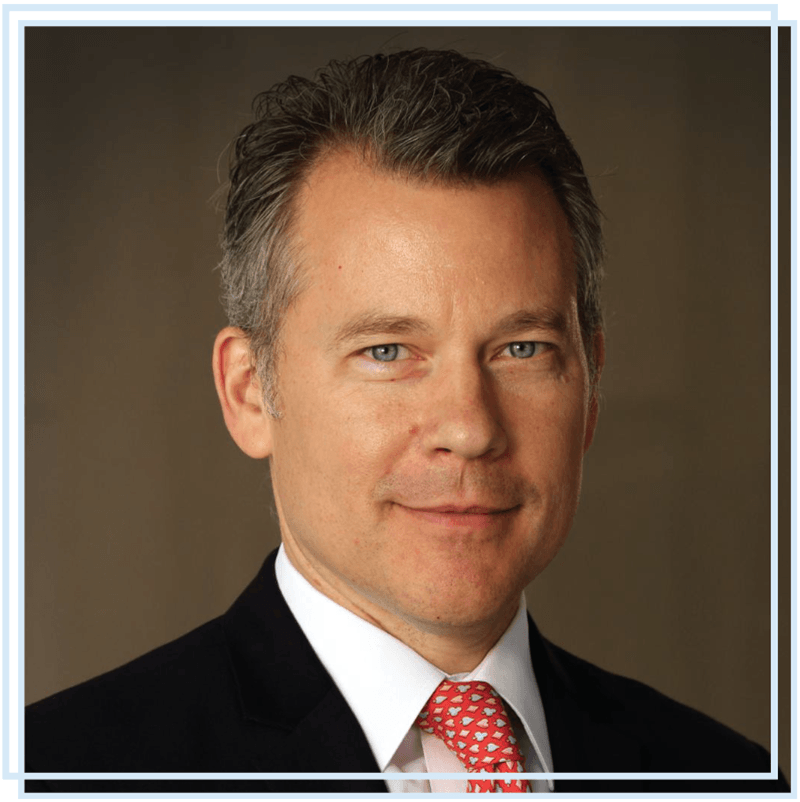 A man in a suit and tie is smiling for the camera