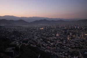 Dusk over a dense city in a mountain valley, with pink sky and distant hills.