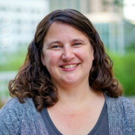 A woman with curly hair is smiling for the camera.
