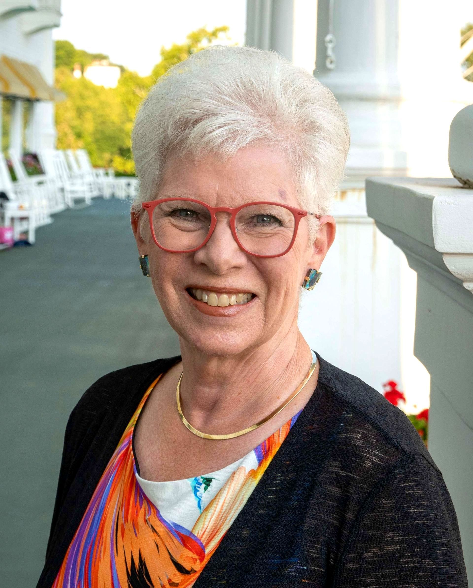 Linda Ketterer, a woman wearing glasses and earrings smiles for the camera
