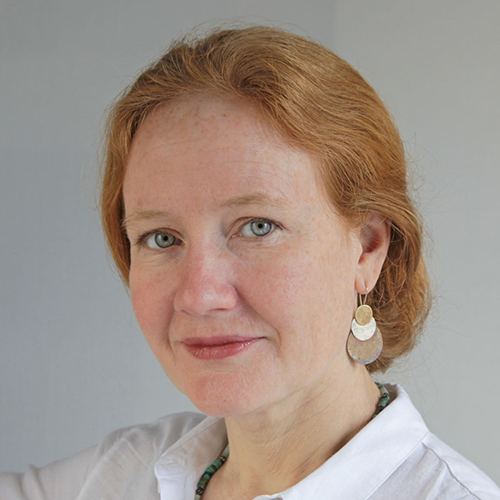 A woman with red hair is wearing a white shirt and earrings