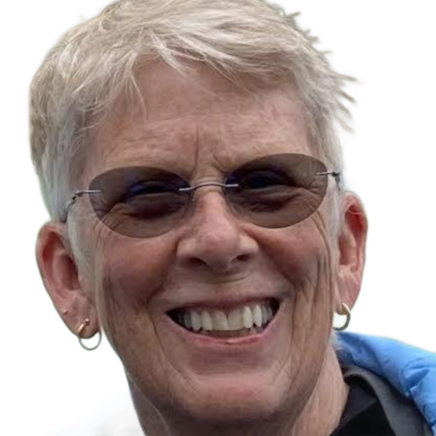 Smiling person wearing sunglasses and a blue jacket in front of a waterfall