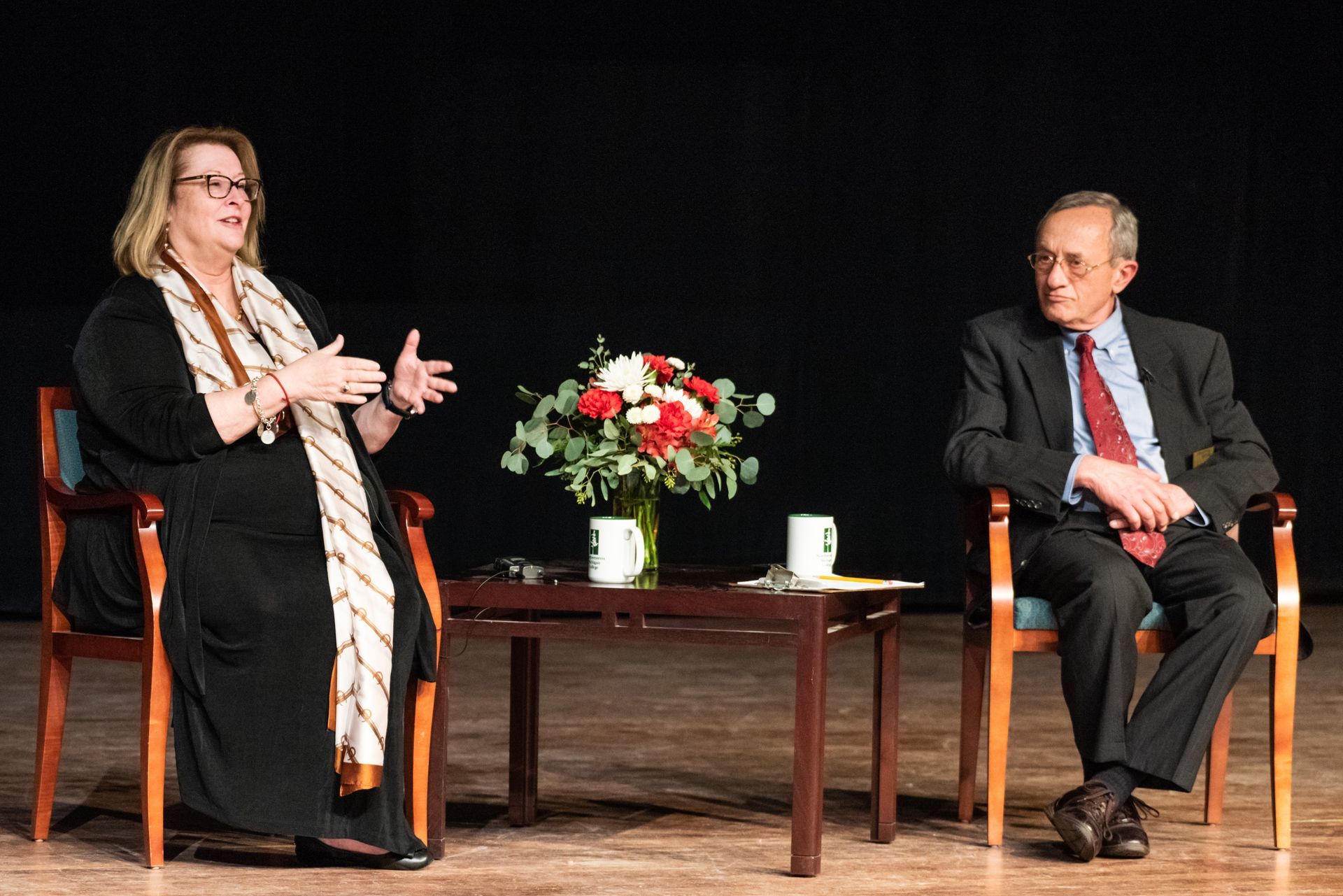 A man and a woman are sitting at a table with a vase of flowers on it