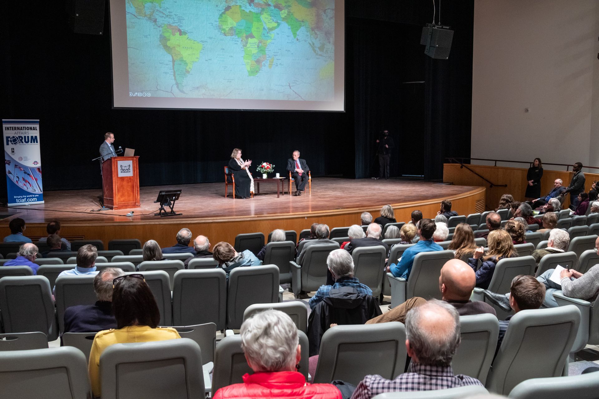 A group of people are sitting in an auditorium watching a presentation.