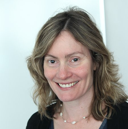 A woman with long hair and a necklace is smiling for the camera.