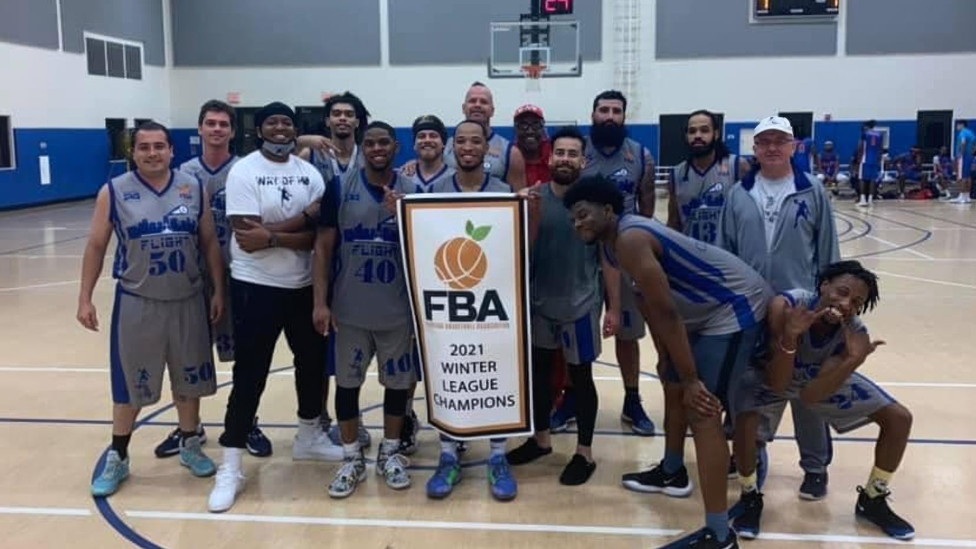 A group of men are posing for a picture on a basketball court.Florida Basketball Association Logo