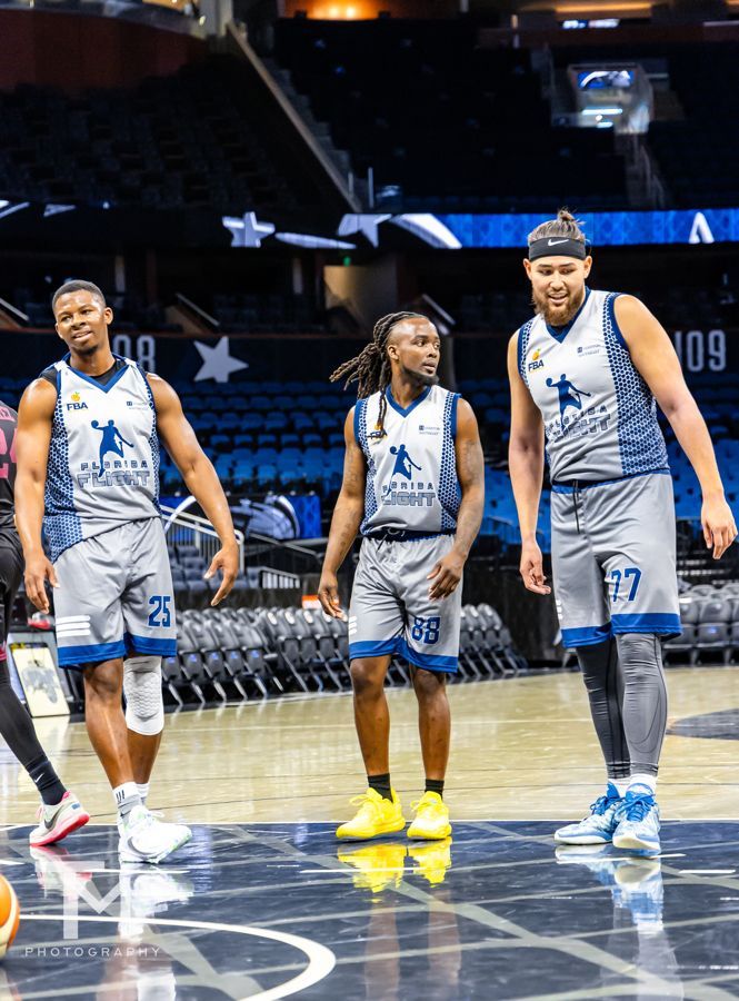 A group of basketball players are standing on a basketball court.