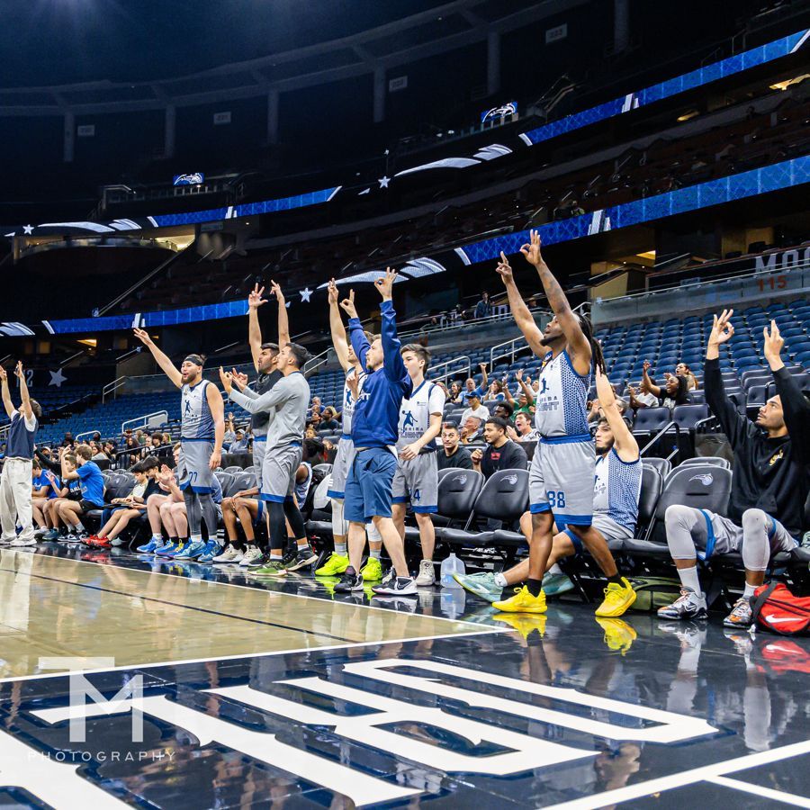 A group of basketball players are standing on a court with their arms in the air.