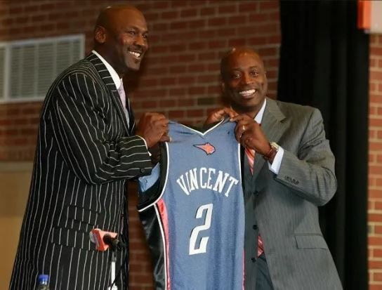 A man in a suit is holding a jersey with the number 2 on it