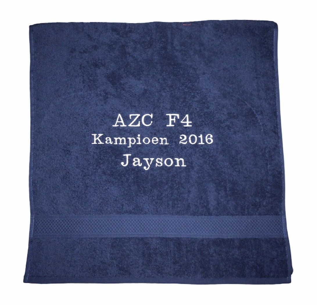 Blauwe geborduurde handdoek met witte tekst: “AZC F4 Kampioen 2016 Jayson”