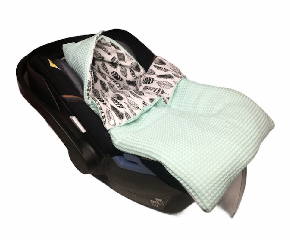 Autostoeltje voor baby's met een mintgroene hoes en een vulling met patroon.