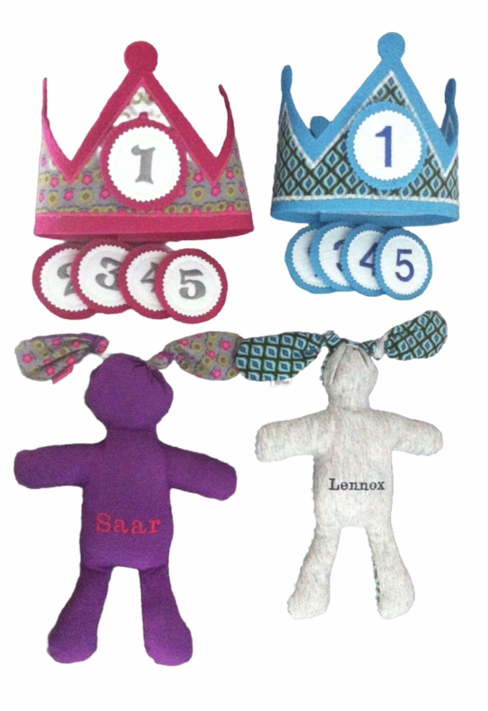 Twee speelgoedkroontjes met genummerde edelstenen en twee kleine pluche poppetjes, een paars en een wit, op een witte achtergrond.