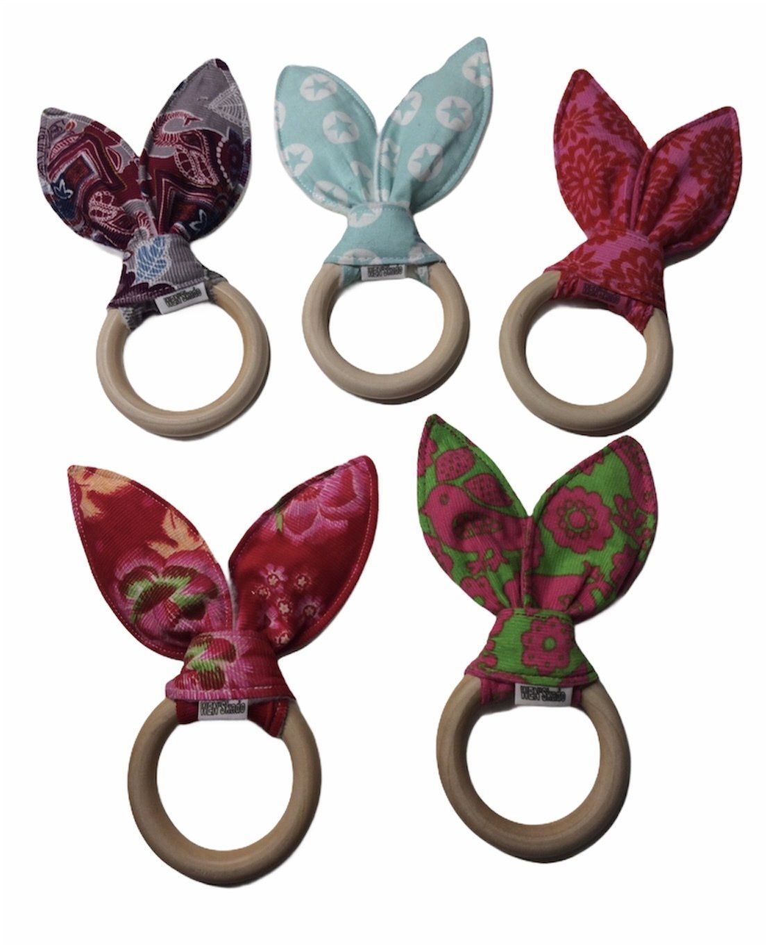 Vijf decoratieve ringhouders in de vorm van konijnenoortjes, in diverse kleuren en patronen, op een witte achtergrond.