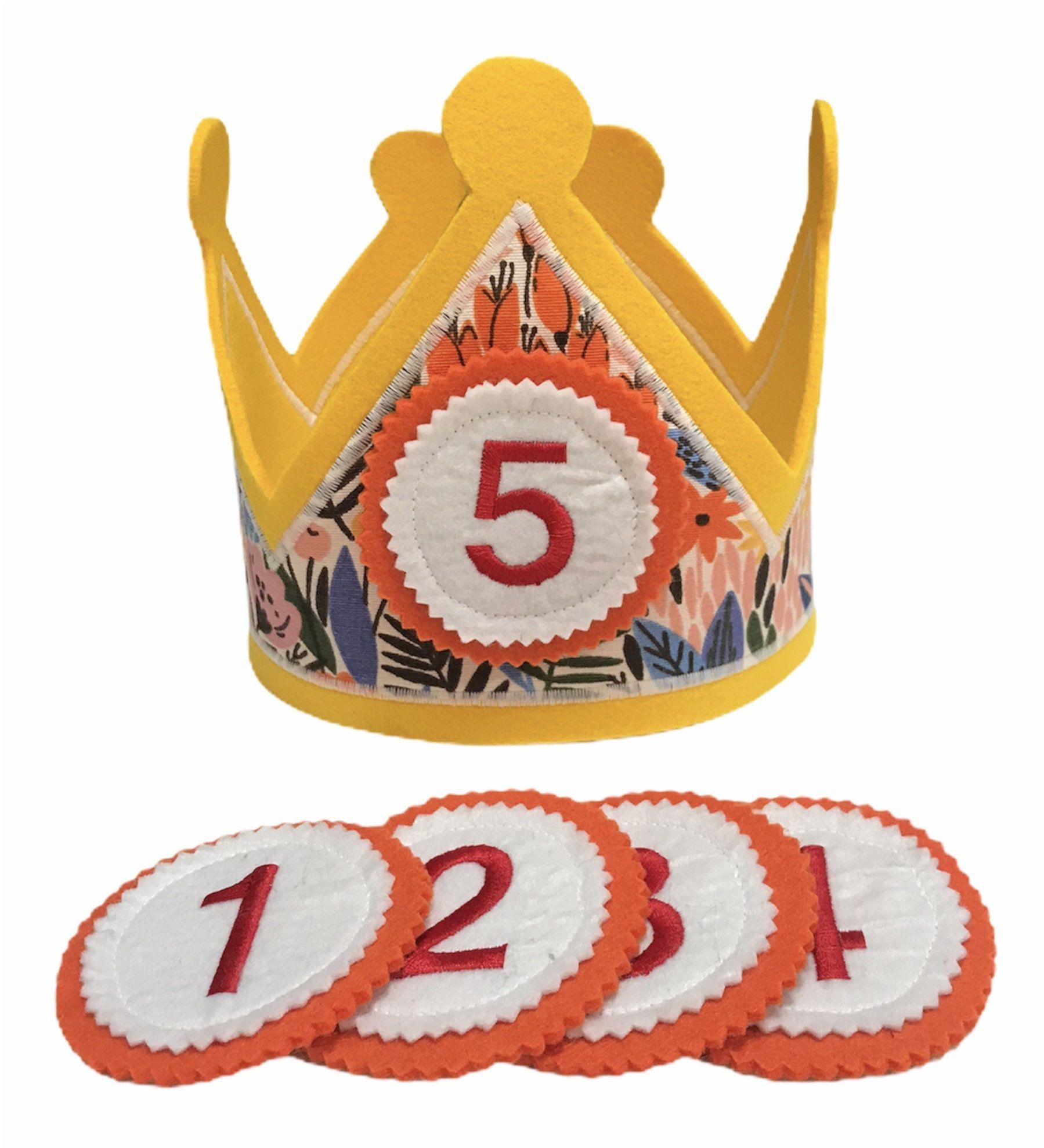 Gouden papieren kroon met een rood-wit embleem met het cijfer 5 erop, en daaronder vijf bijpassende, genummerde emblemen.