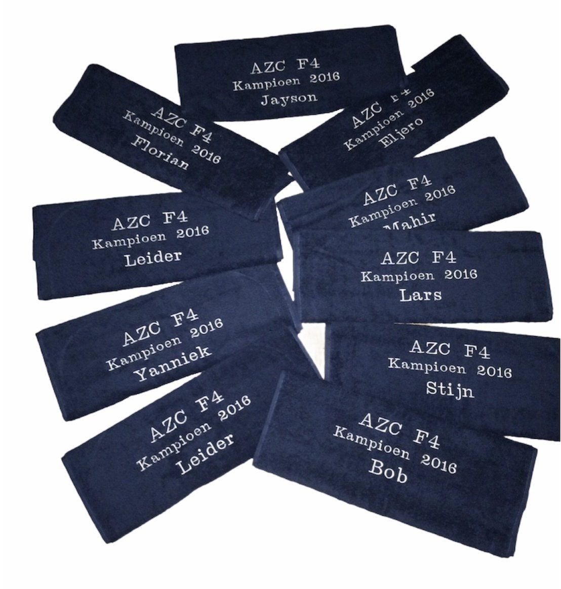 Diverse donkerblauwe stoffen labels met witte geborduurde tekst, verspreid over een hoopje.