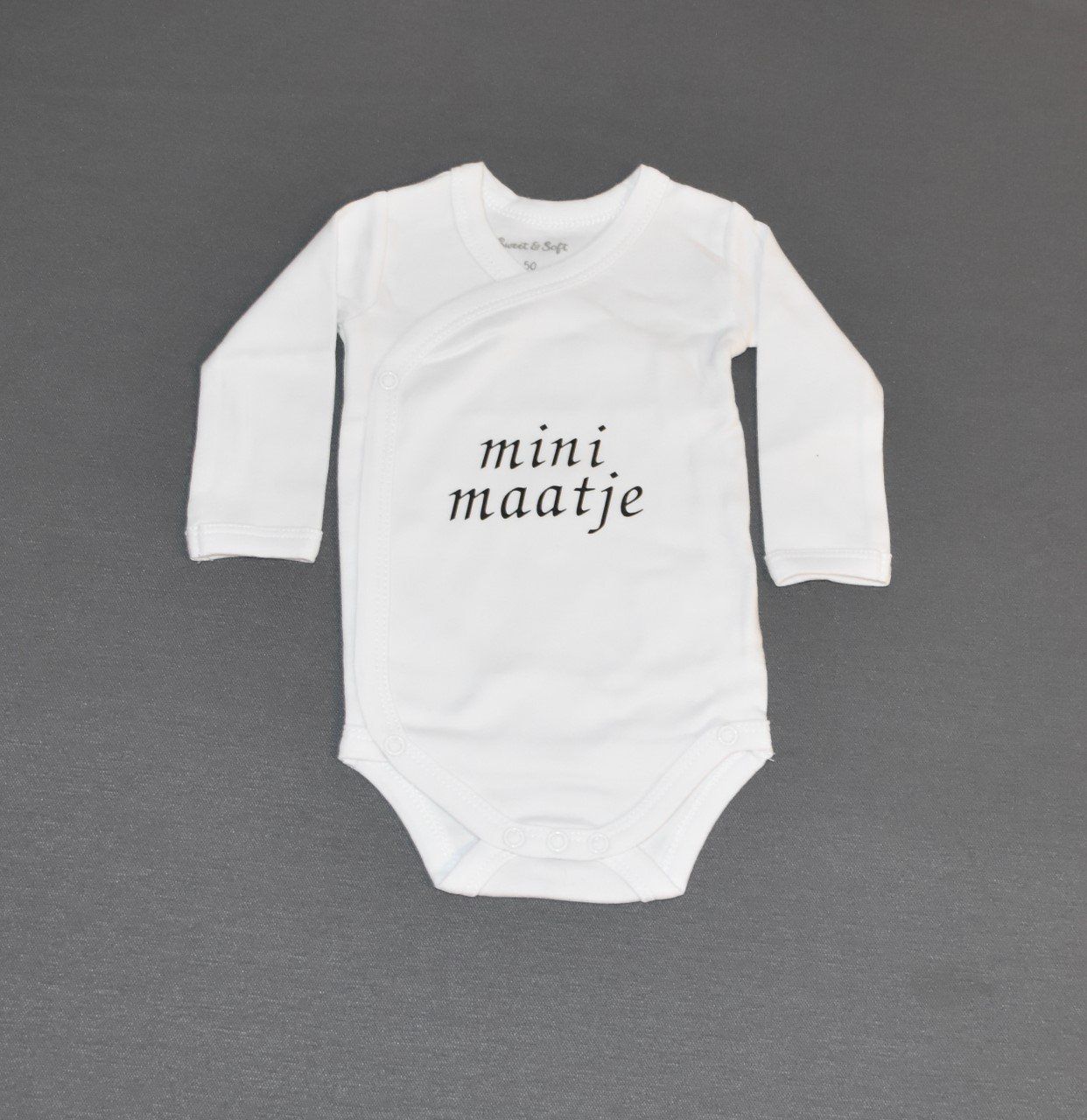 Witte babyromper met lange mouwen en de tekst 
