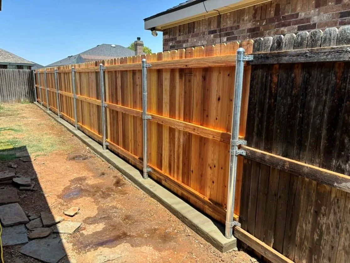 New wooden fence alongside a weathered wooden fence, both in a backyard.