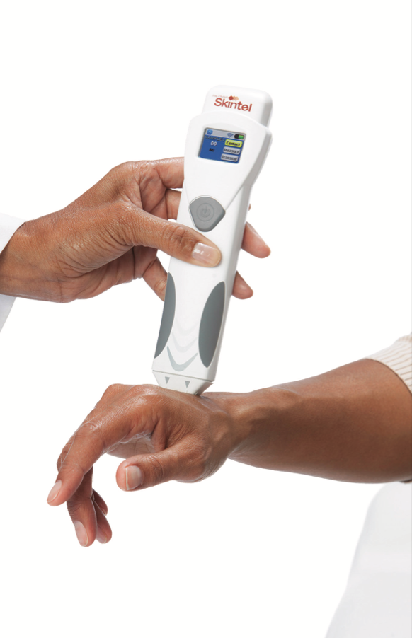Handheld medical device being used on a patient's wrist.