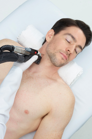 Man receiving neck laser treatment on a medical table, eyes closed.