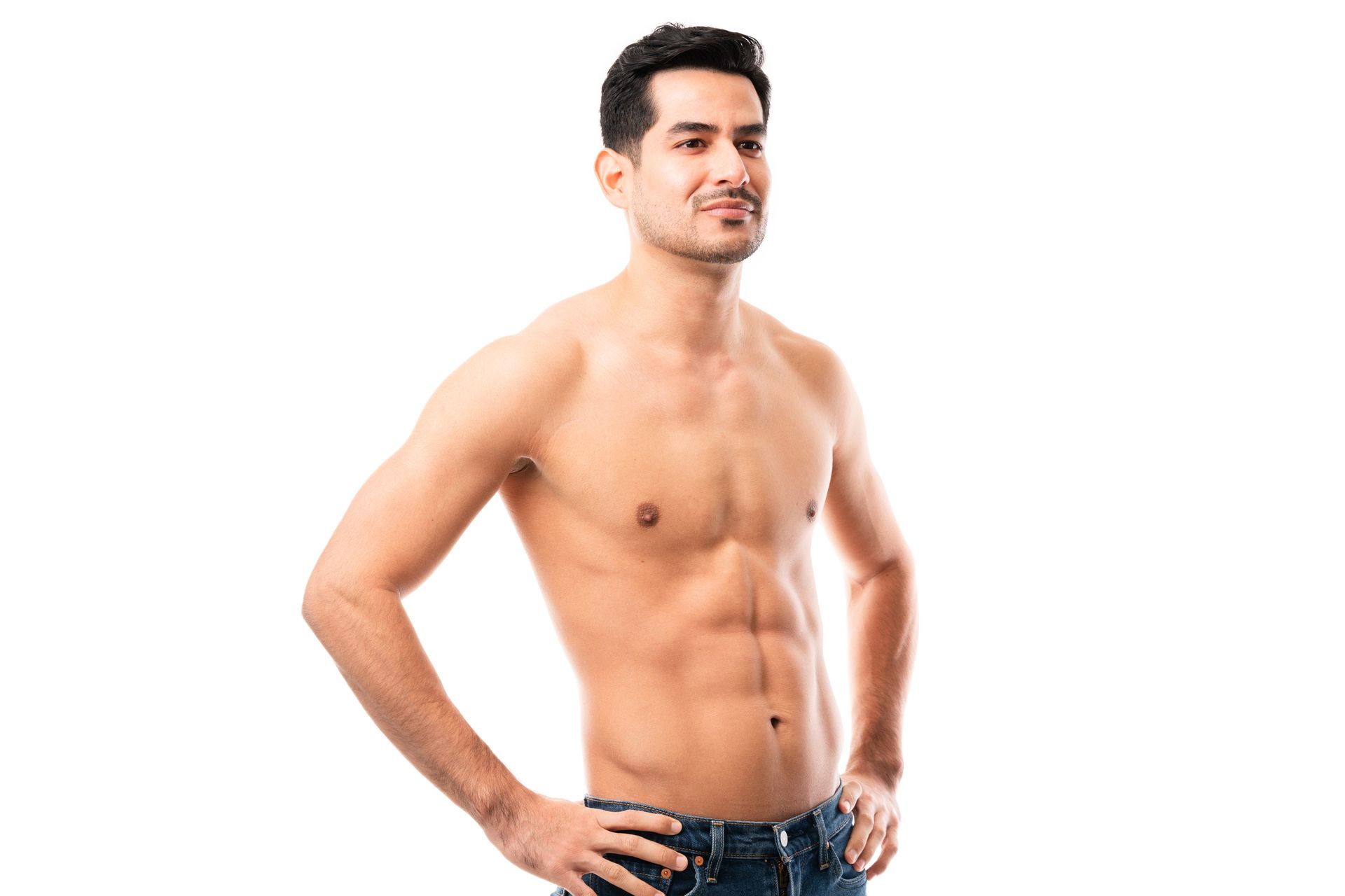 Man with toned torso, hands on hips, smiling, wearing jeans, against white background.
