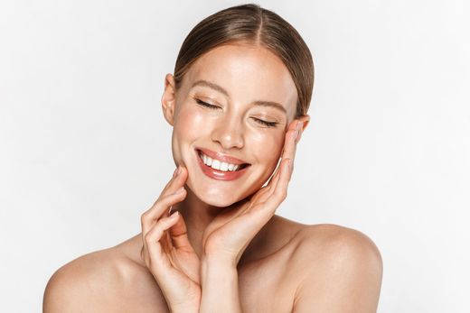 Woman smiles with hands on face, radiant skin.