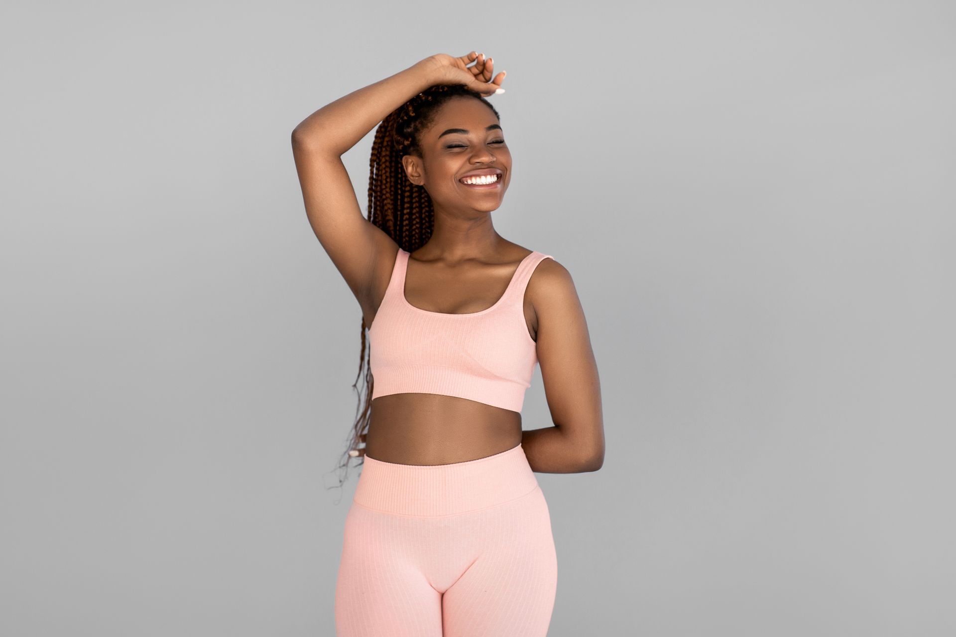 Woman in peach athletic wear smiles with one arm raised.