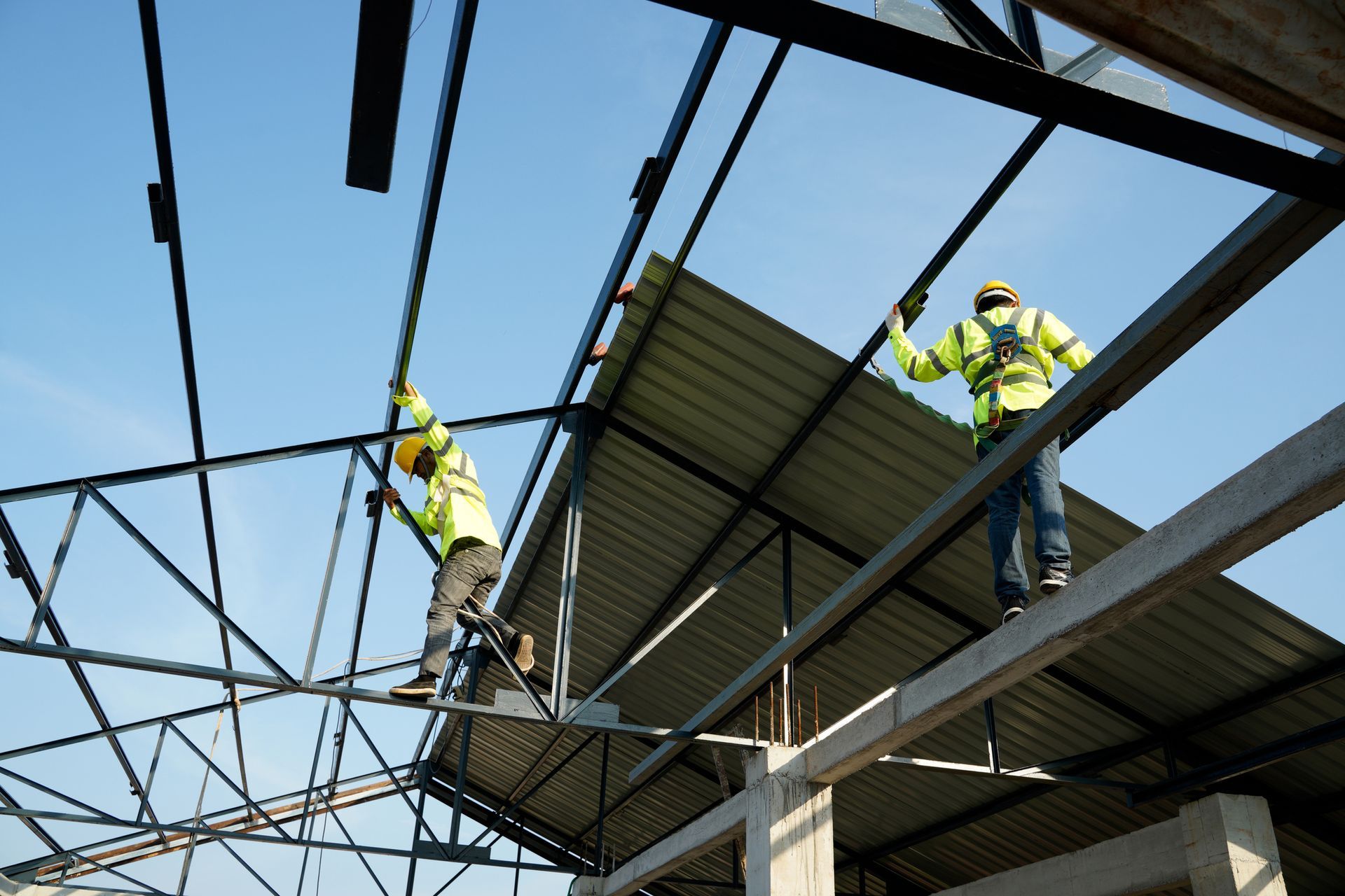 Two roofing contractors are working on a roof installation.