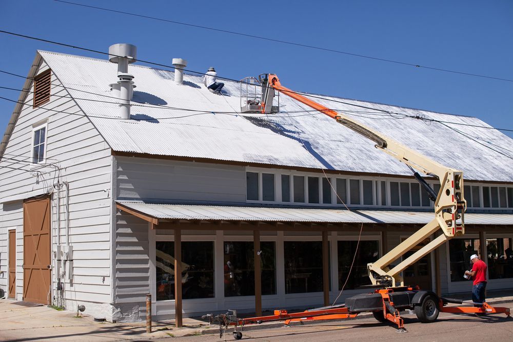 Workers Reroofing White Building Roof — SRV Roofing in Hervey Bay, QLD