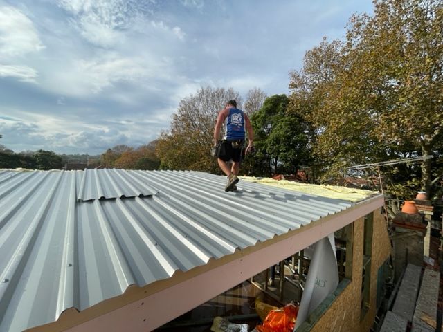 Man With A Blue Top Walking On The Roof — SRV Roofing in Maroochy River, QLD