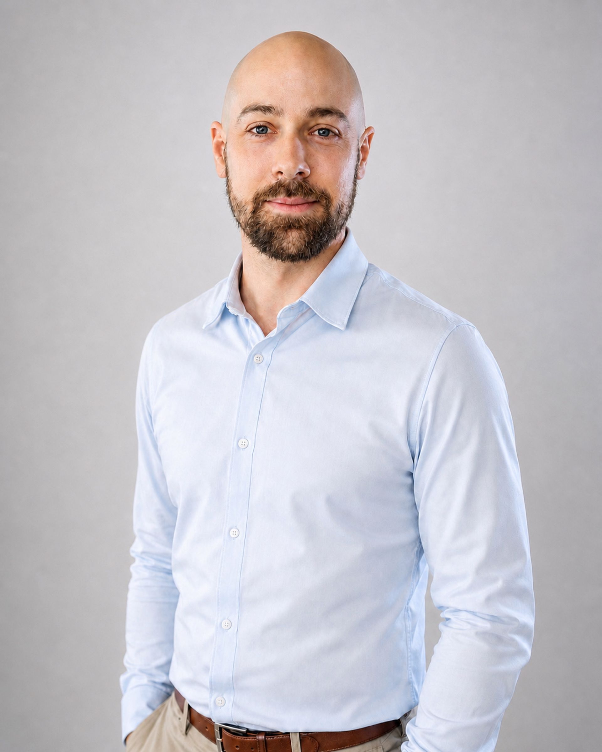 Portrait d’un homme chauve en chemise bleu clair sur fond gris