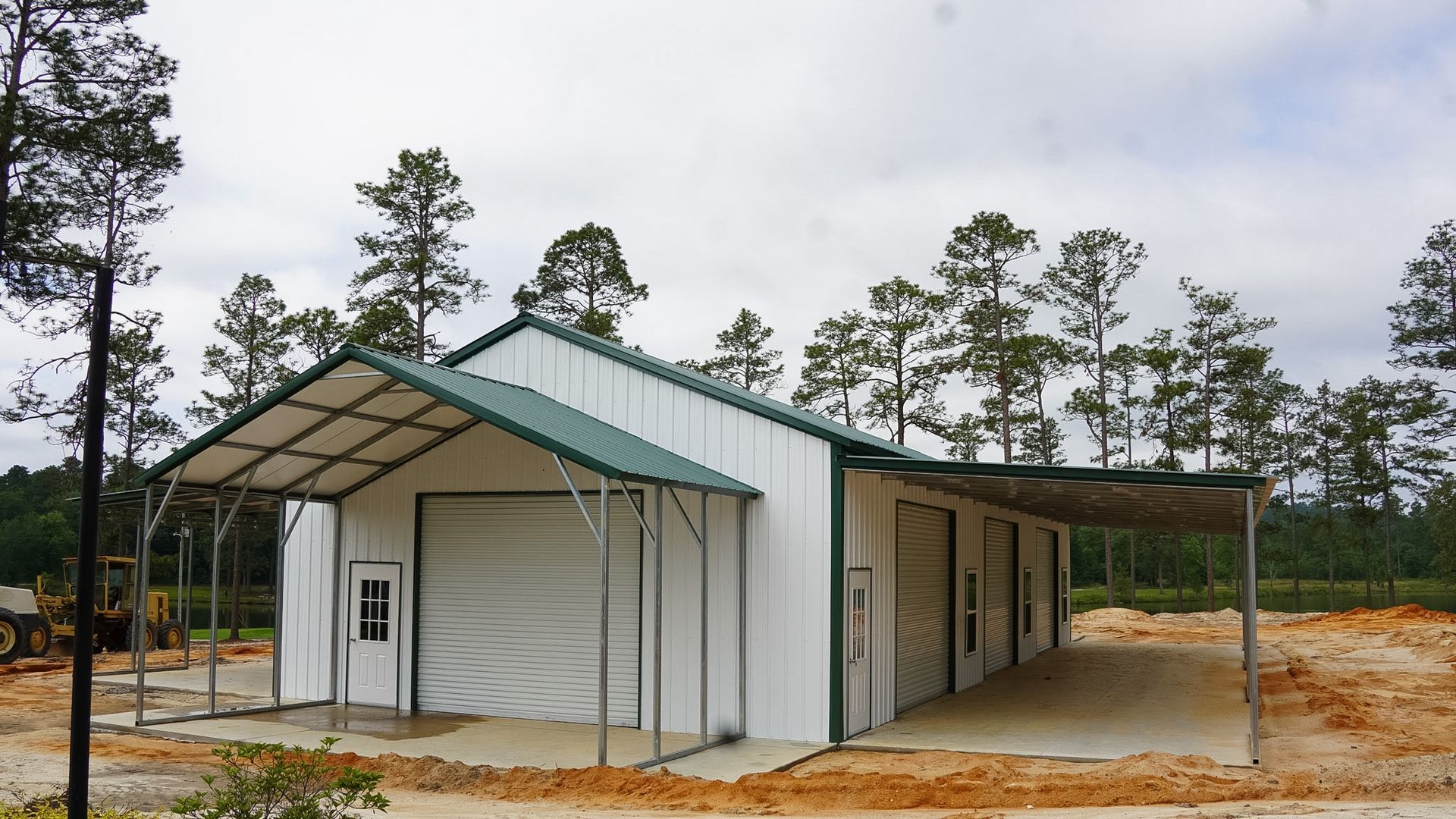 Small white building with green roof and covered porch in a wooded, sandy clearing
