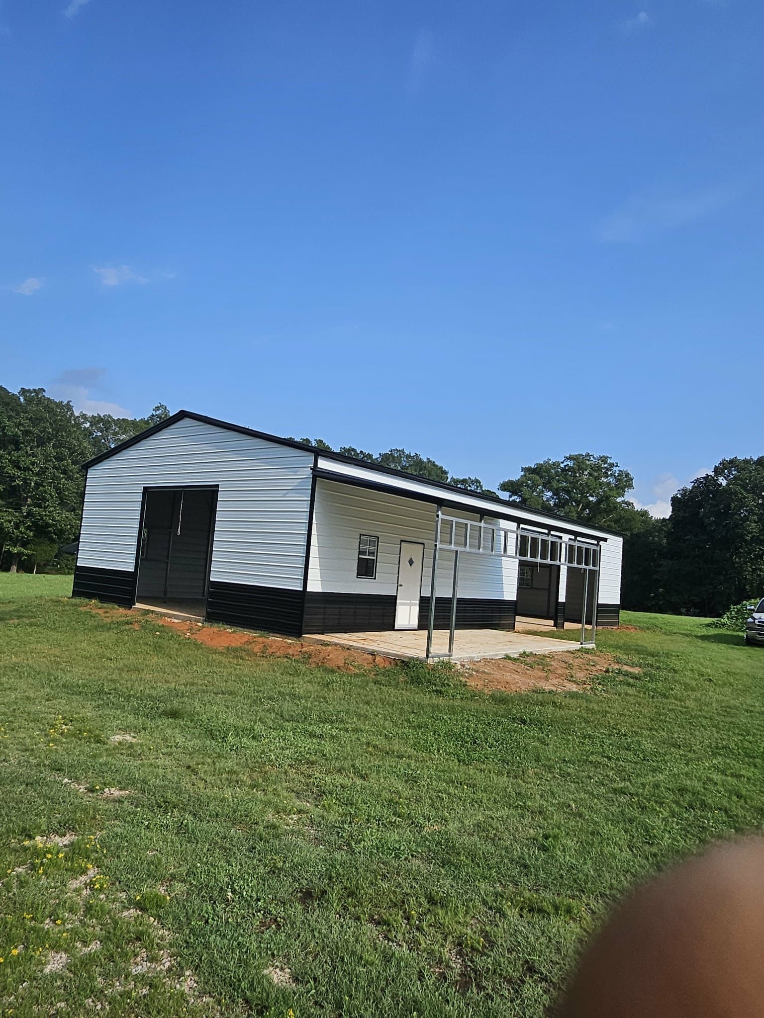 Small white house with a porch on a grassy lot under a clear blue sky.