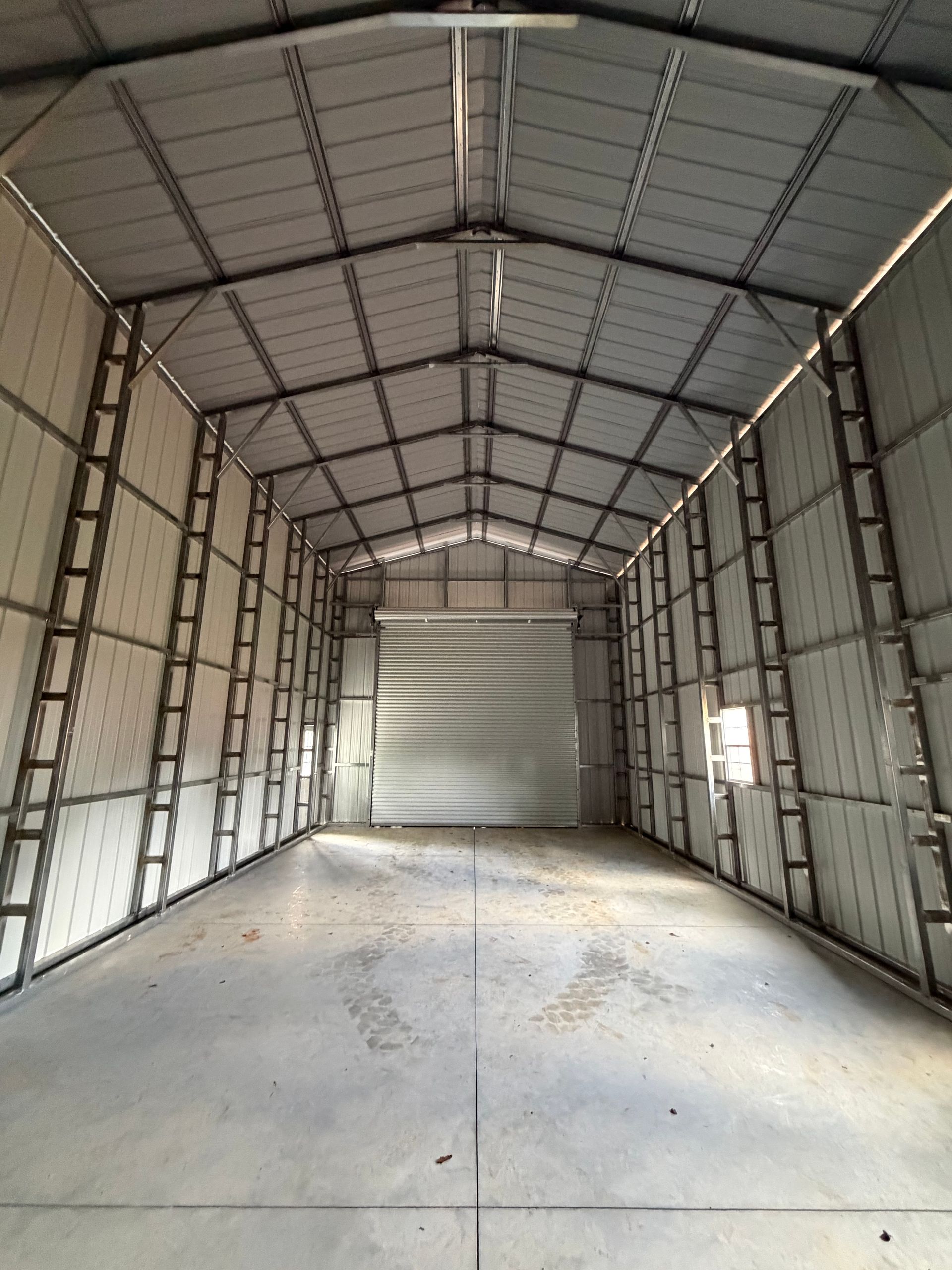 Empty metal warehouse interior with concrete floor and open end wall