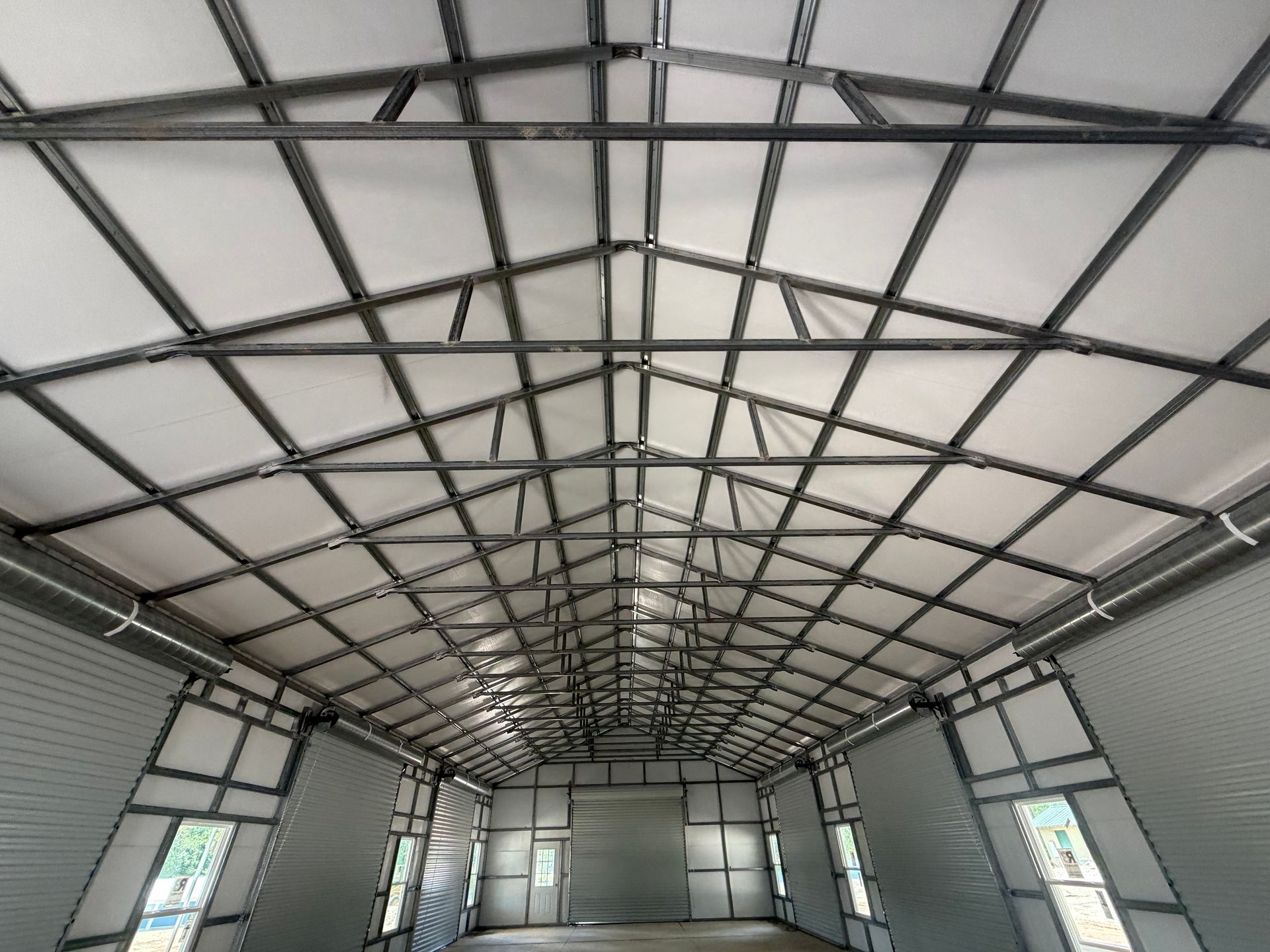 Interior of an empty metal-framed warehouse with a high arched roof and skylight panels