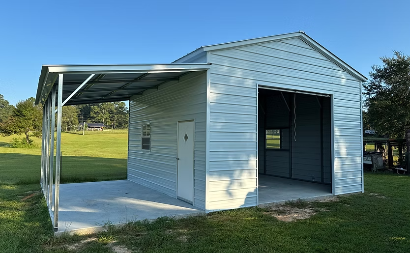 Small white metal shed with an open front, side porch roof, on a grassy field under a blue sky