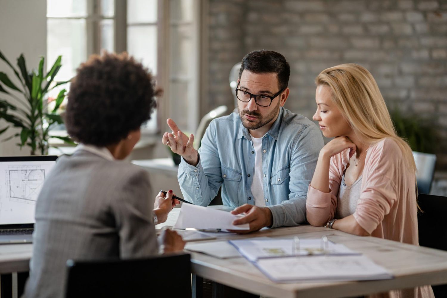 Couple discussing documents with a professional at a table; office setting.